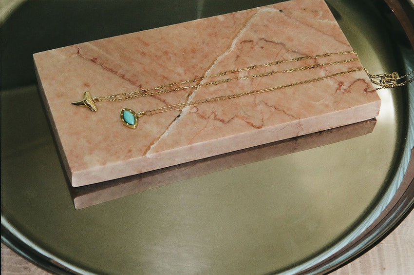 The shark tooth charm on a figaro chain and the secret eye charm in turquoise on a Forza chain.