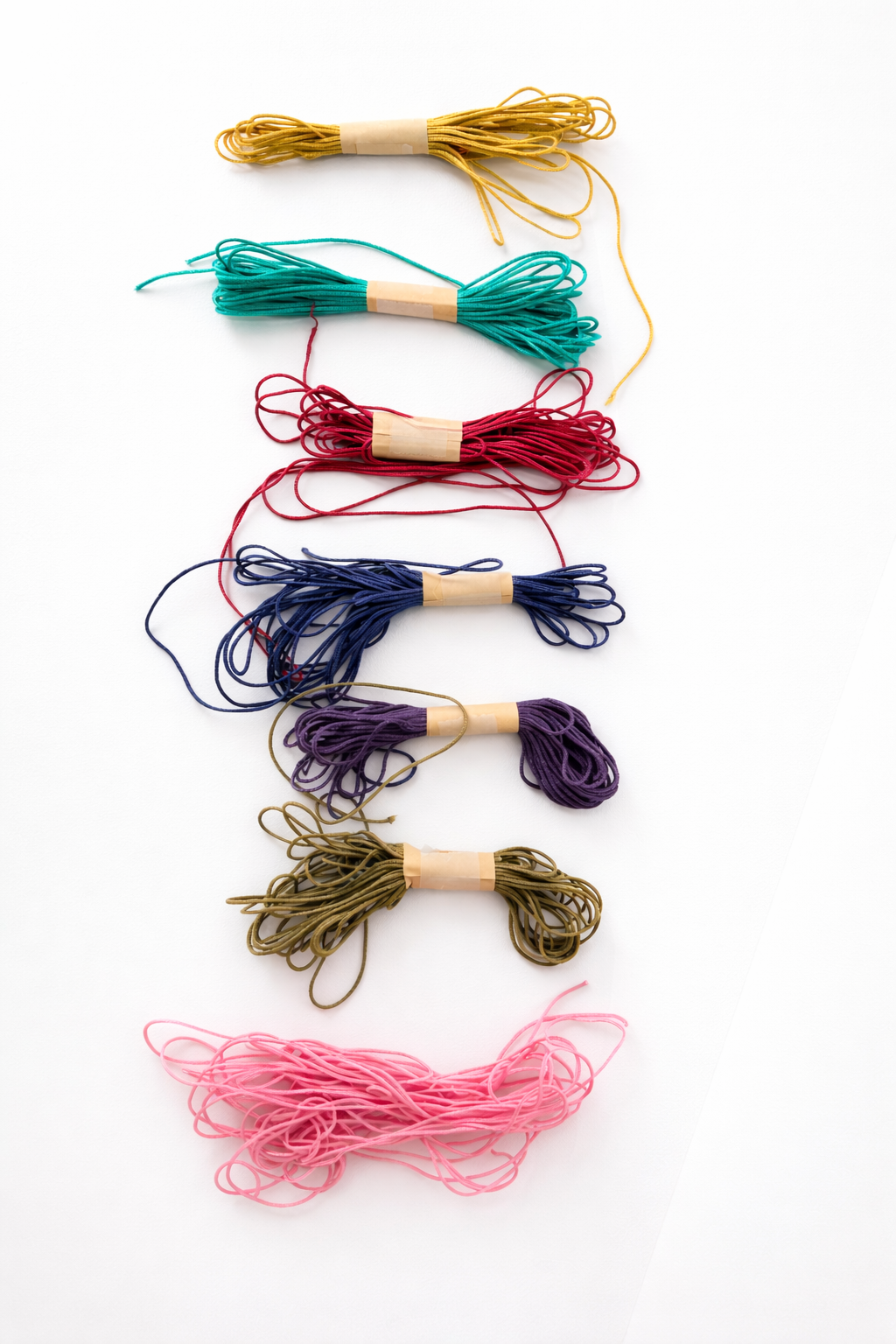 Set of colorful embroidery threads on wooden spools against white background